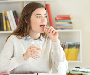 wanita sedang minum suplemen maitake